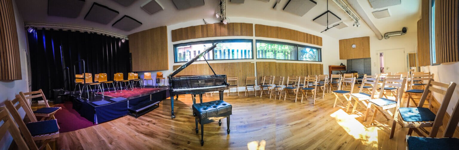 Wide view of the performance hall at o-ton Musik&Projektsaal, Cologne, with rows of chairs and a grand piano