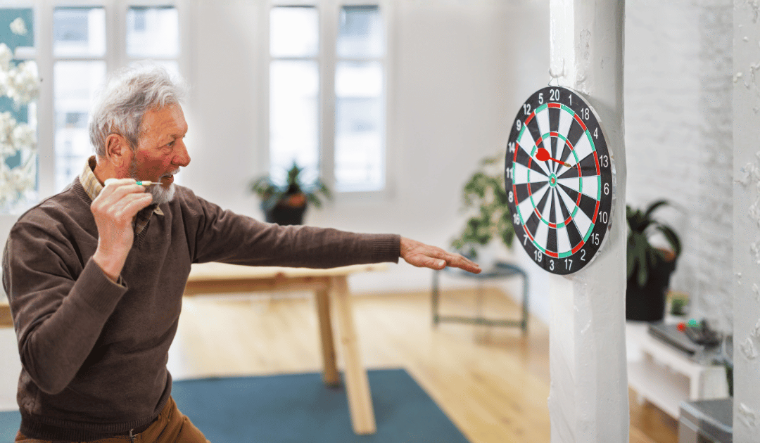 Older man aiming a dart at a dartboard, like aiming for a leap at the piano
