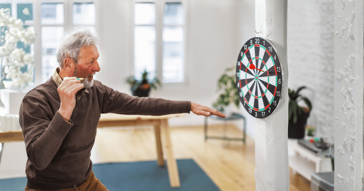 Older man aiming a dart at a dartboard, like aiming for a leap at the piano